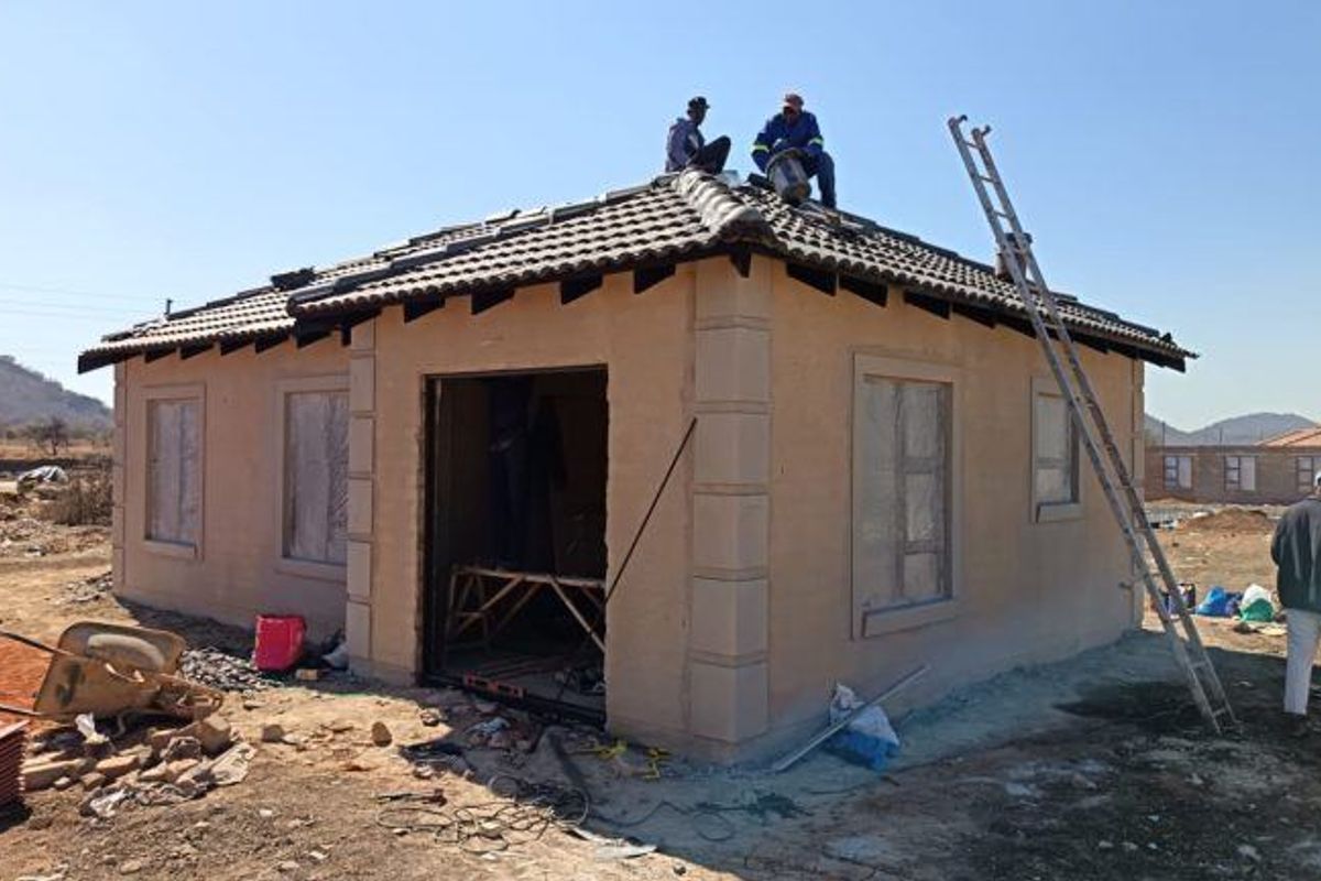 A single-story residential property under construction, featuring a tiled roof and plastered exterior walls with decorative quoins.