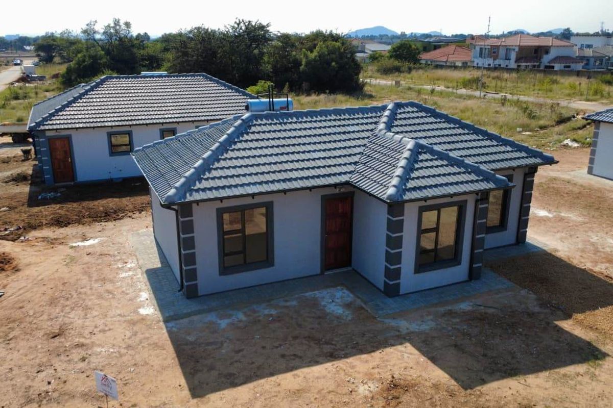 Aerial view of a newly constructed single-story residential house featuring a tiled roof, solar geyser, and paved apron in a developing estate.