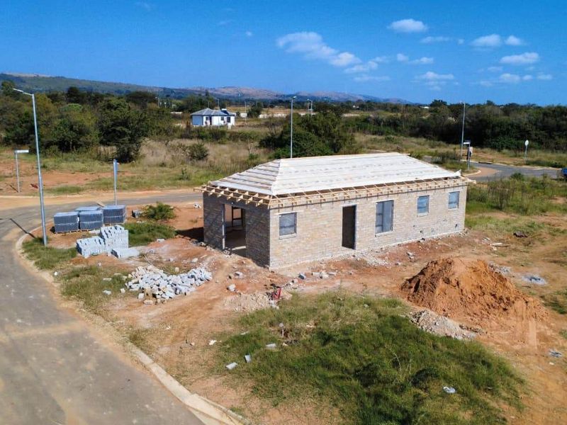 Aerial view of a residential property currently under construction, featuring brick walls and timber roof trusses on a large corner plot.