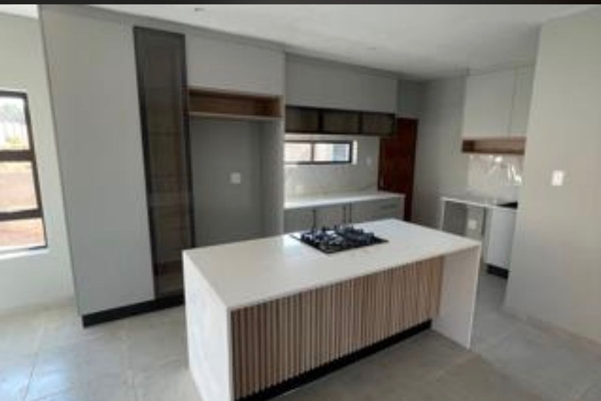 Modern kitchen featuring a central island with a gas hob, stone countertops, and contemporary cabinetry with slatted wood detailing.