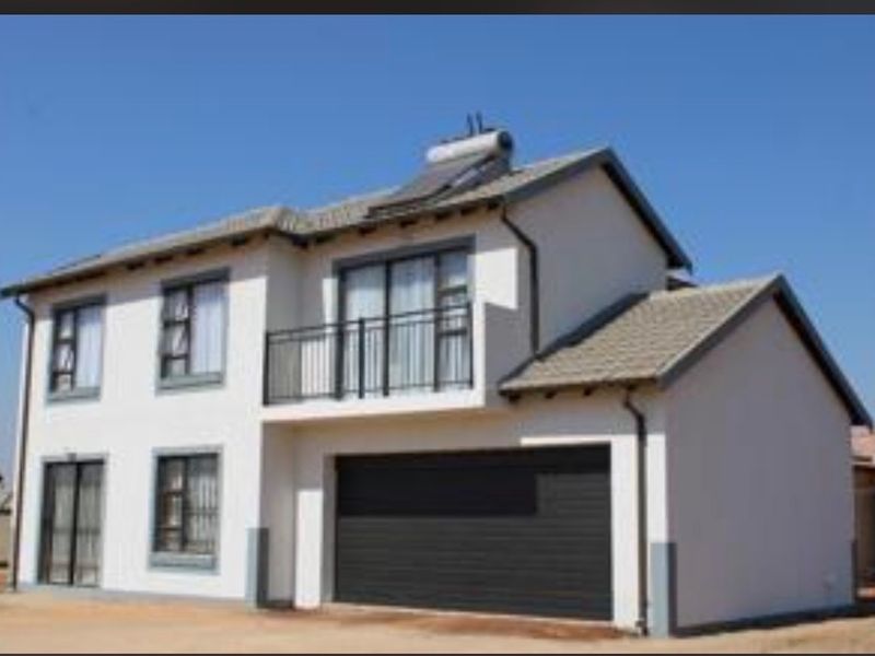 A modern double-storey residential house featuring a tiled roof, solar water heating system, balcony, and a secure garage.