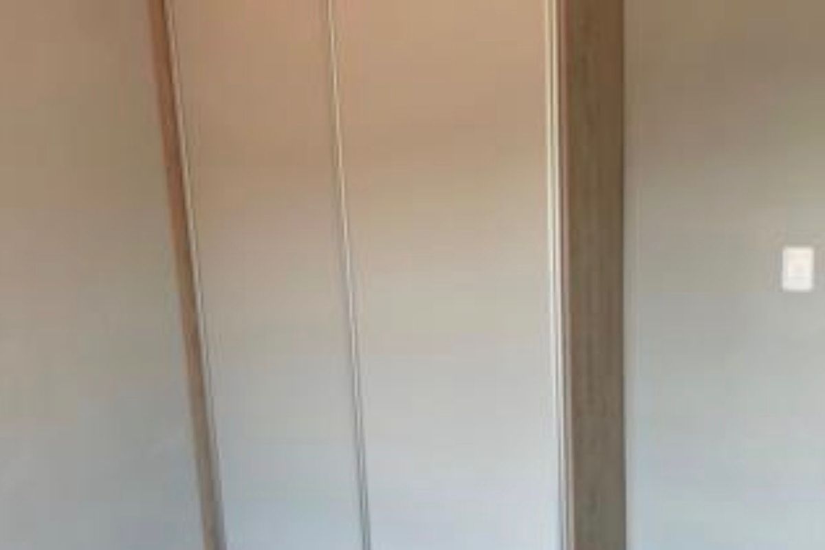 A bedroom featuring a built-in wardrobe with light-toned wood trim and neutral-colored sliding doors.