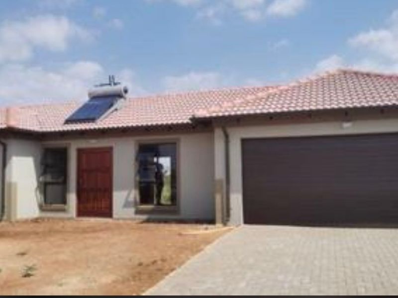 Front elevation of a modern single-story house featuring a tiled roof, solar water heating system, integrated garage, and paved driveway.