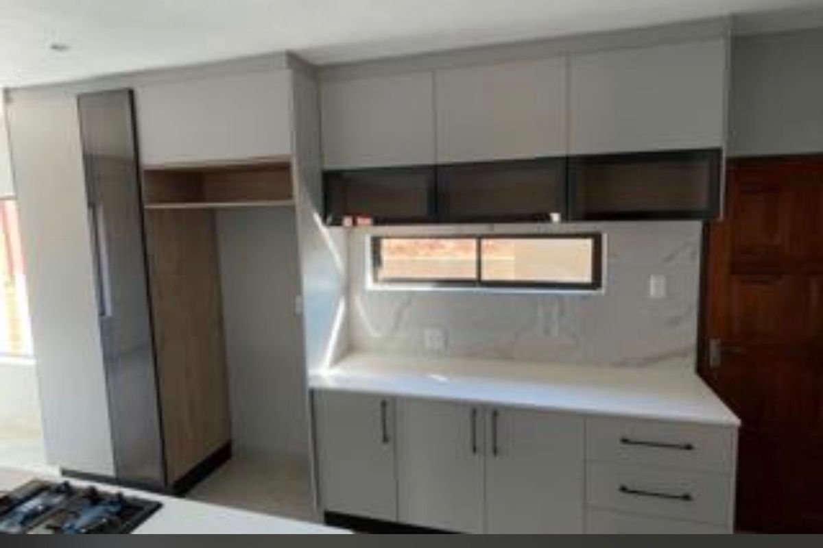 Modern kitchen featuring sleek grey cabinetry, stone countertops, marble-look splashback, and integrated appliance housing in a clean, contemporary finish.