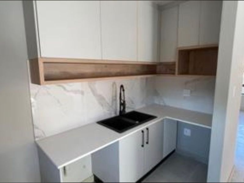 Modern scullery featuring sleek white cabinetry, stone countertops, a double basin sink with a black mixer tap, and a stylish marble-look splashback.