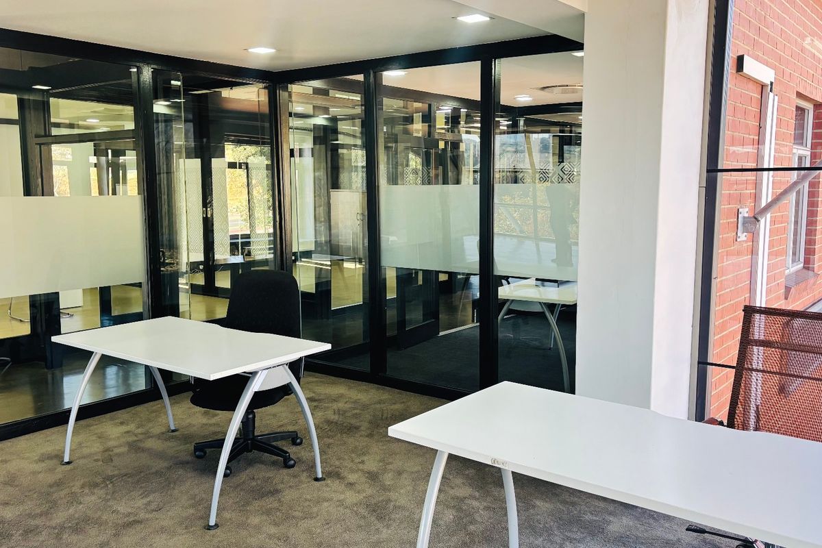 Modern commercial office space featuring glass partition walls, recessed lighting, and exposed brickwork, providing a professional and bright working environment.