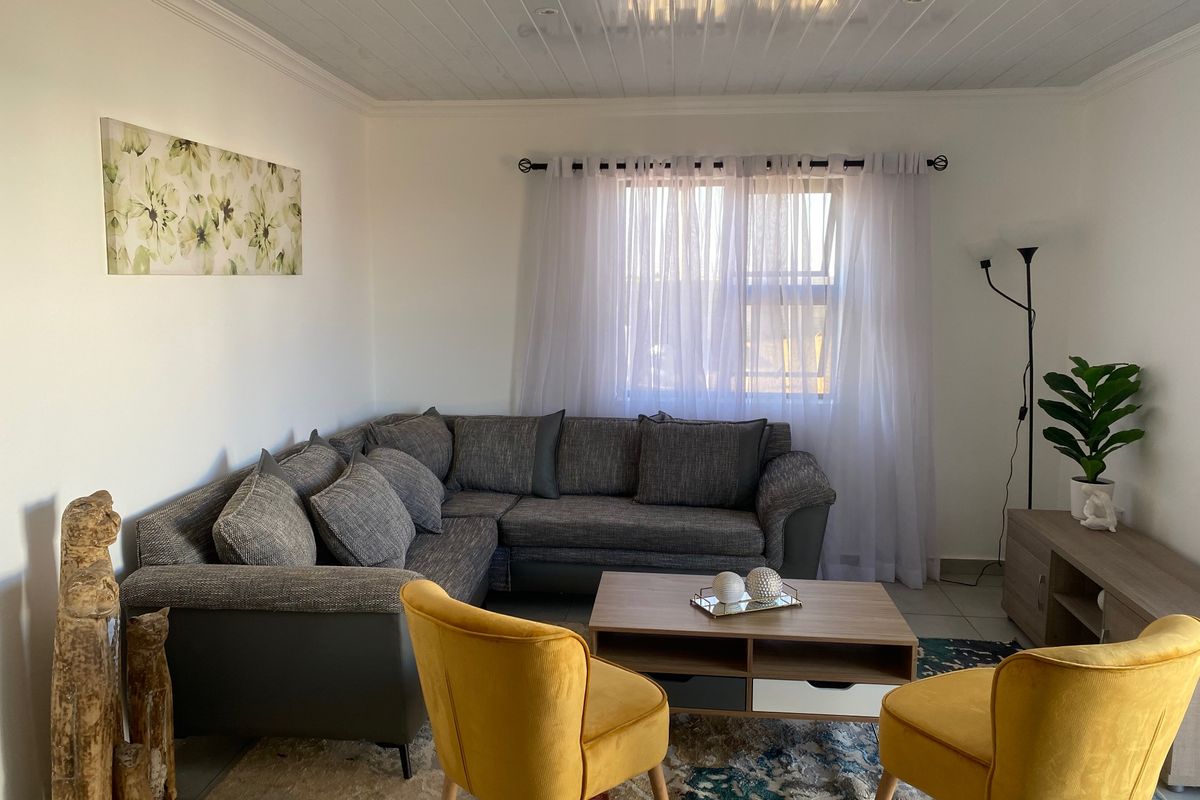 A well-maintained living room featuring tiled flooring, a tongue and groove ceiling, and recessed downlighting, creating a comfortable and inviting space.