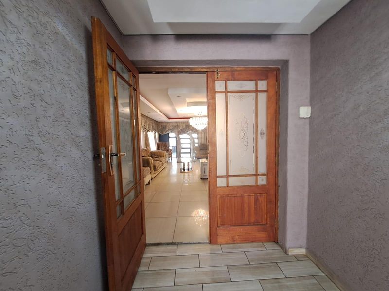 Entrance foyer featuring double timber doors with frosted glass panels, leading into a spacious living area with tiled flooring and recessed ceiling details.