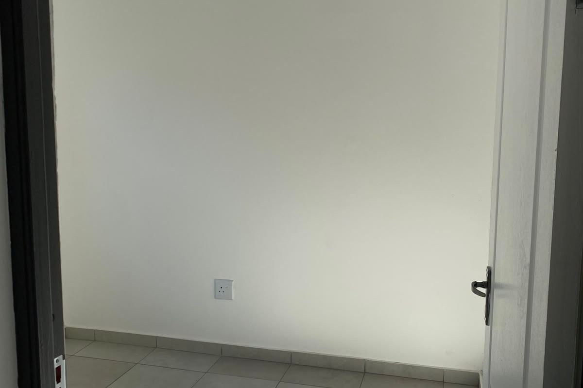 A bright, empty bedroom featuring neutral tiled flooring, a white tongue and groove ceiling with recessed lighting, and clean wall finishes.