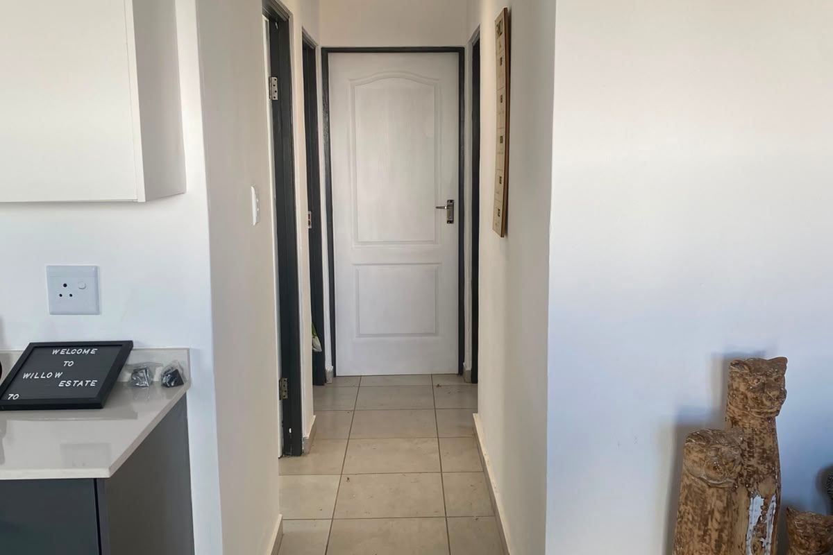 A clean, well-lit hallway featuring neutral tiled flooring and multiple interior doors leading to various rooms within the home.