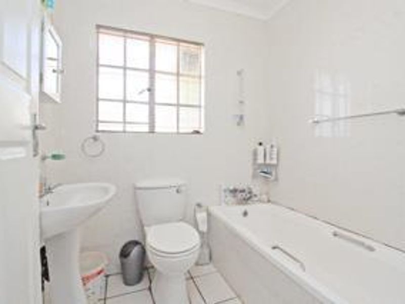 A functional bathroom featuring a pedestal basin, toilet, and bathtub with tiled walls and flooring, providing a clean and practical space.