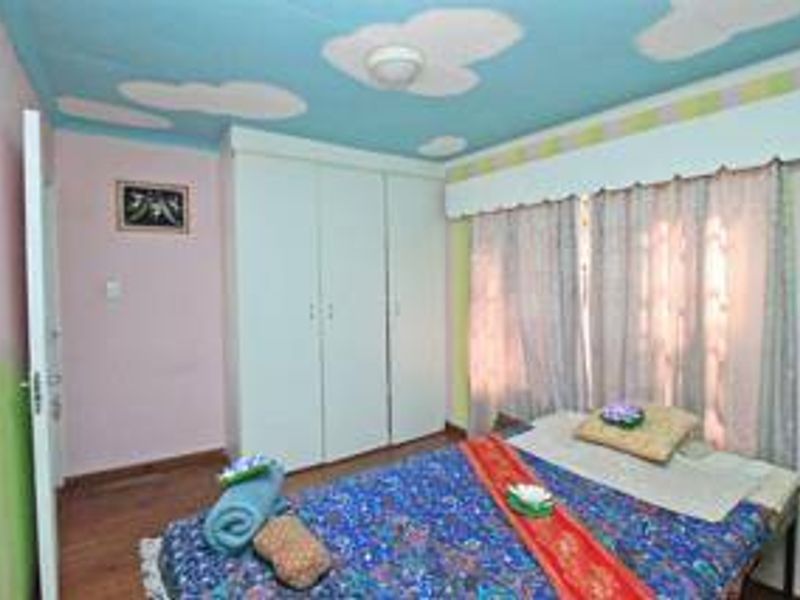 A bedroom featuring built-in cupboards, laminate flooring, and a unique painted ceiling design. The room requires cosmetic updates to modernize the interior finishes.