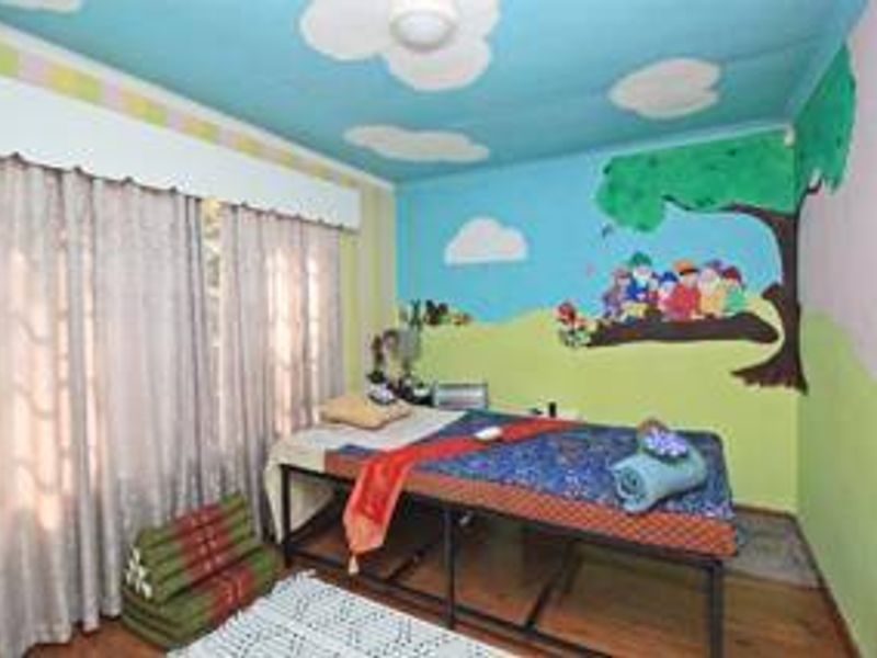 A bedroom featuring painted wall murals and ceiling decorations, currently set up as a treatment room.