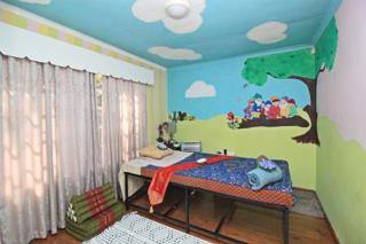 A bedroom featuring painted wall murals and ceiling decorations, currently set up as a treatment room.