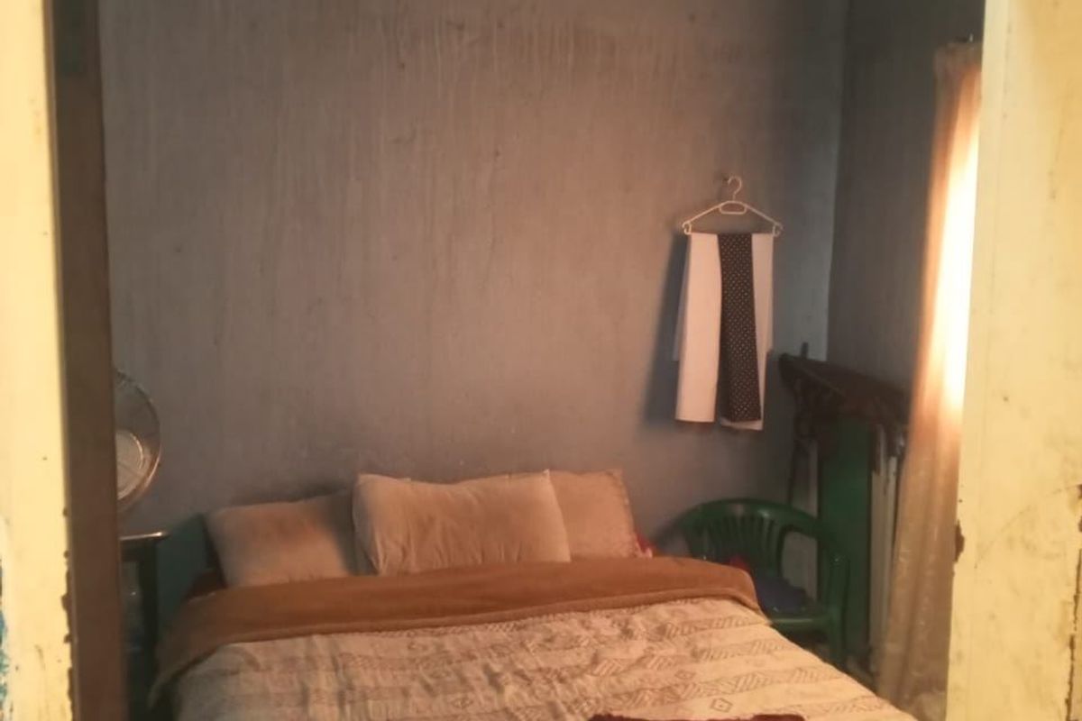 A bedroom featuring an exposed corrugated metal ceiling and plain wall finishes, requiring cosmetic updates to improve the overall aesthetic and condition.