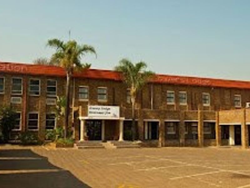Front exterior view of a commercial brick building featuring a paved parking area and a covered entrance.