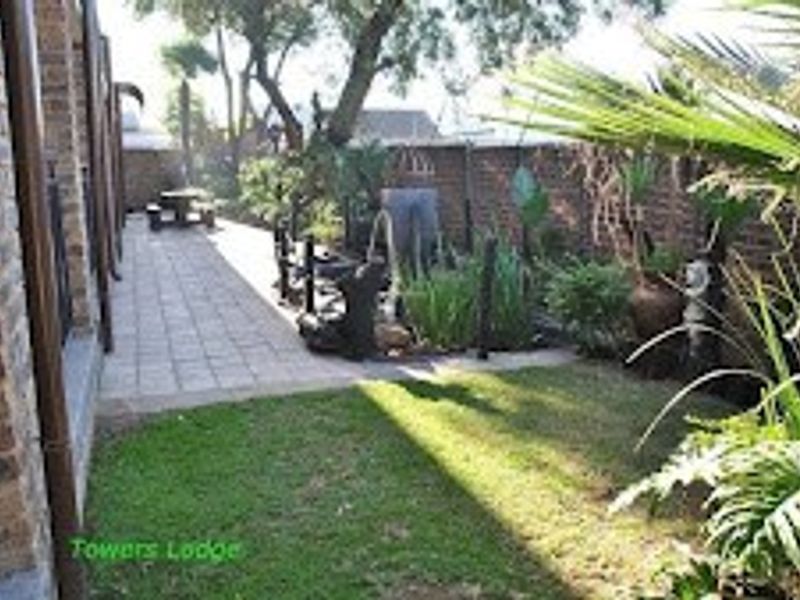 A rear garden area featuring a paved walkway, lawn, and brick boundary wall, providing outdoor space for the commercial property.