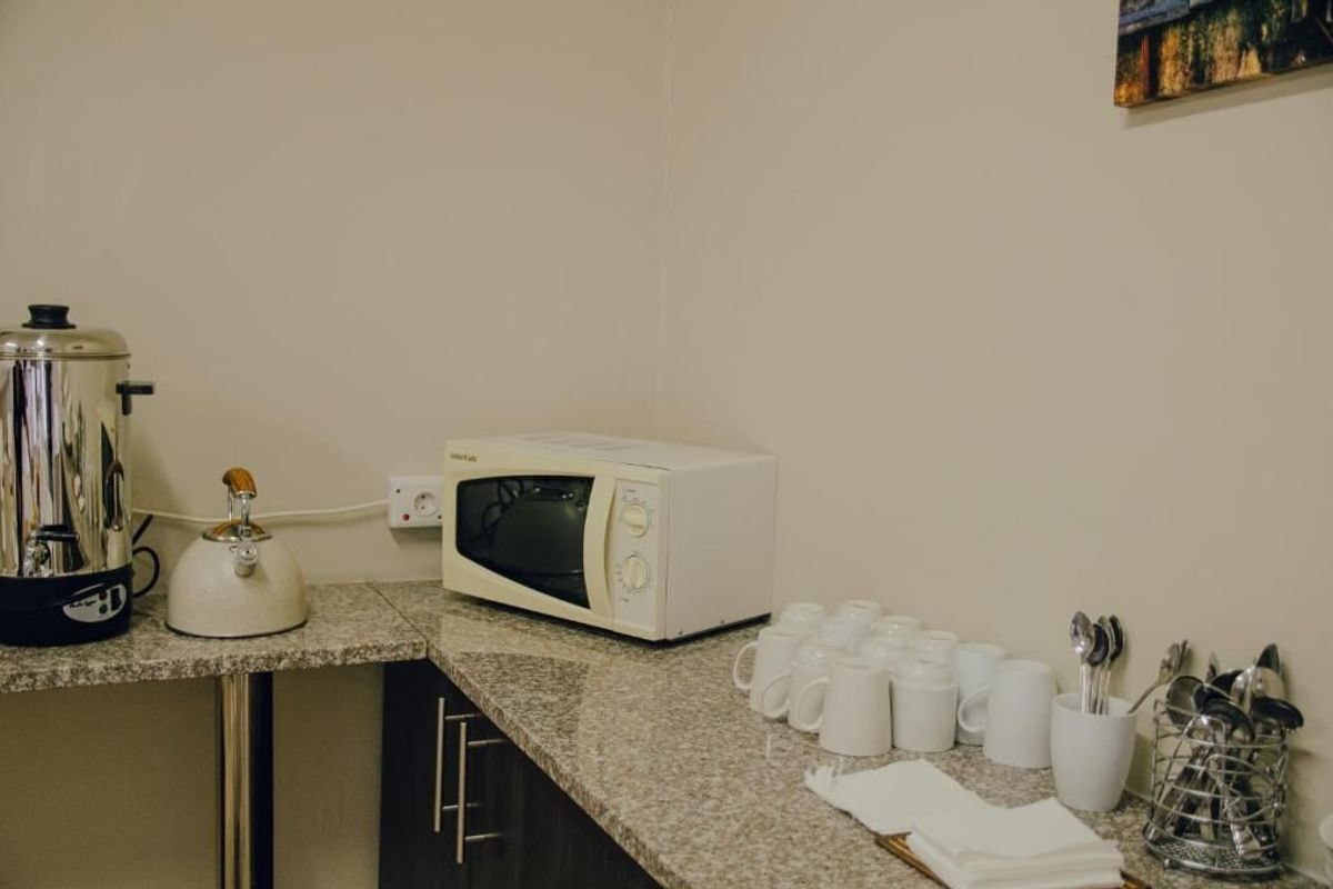 A functional kitchenette area featuring granite countertops and built-in cabinetry, suitable for office or commercial breakroom use.