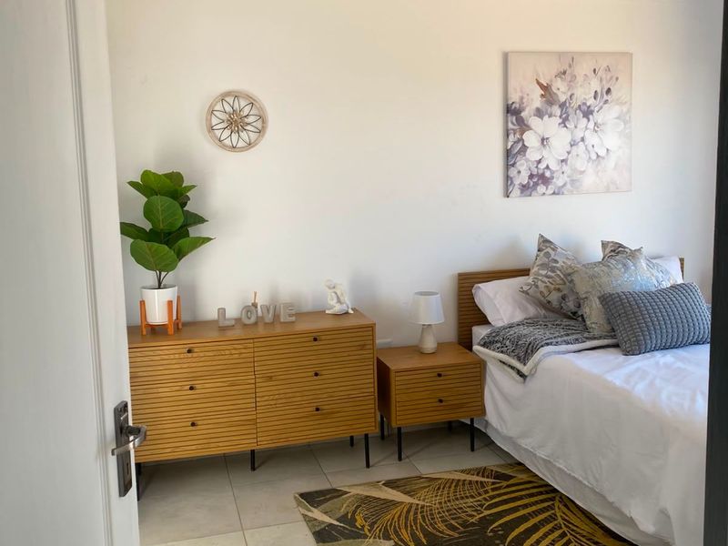 A well-maintained bedroom featuring neutral tiled flooring and a white tongue and groove ceiling, offering a clean and comfortable living space.
