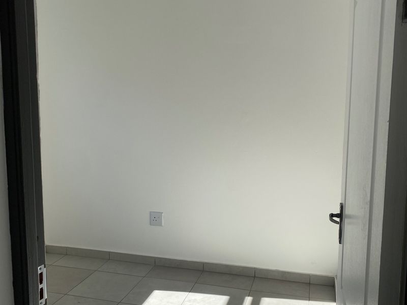 A bright, empty bedroom featuring neutral tiled flooring and a white tongue and groove ceiling, ready for personalization.