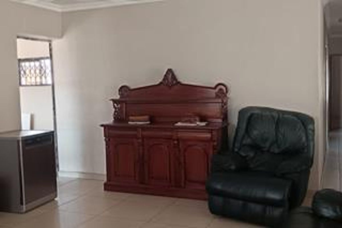 A living area featuring neutral wall finishes and tiled flooring, providing a functional space with access to adjacent rooms.
