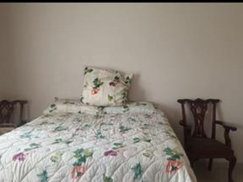 A simple bedroom space with neutral walls and tiled flooring.