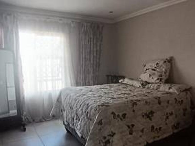 A functional bedroom featuring tiled flooring, recessed ceiling lights, and a sliding glass door providing natural light.