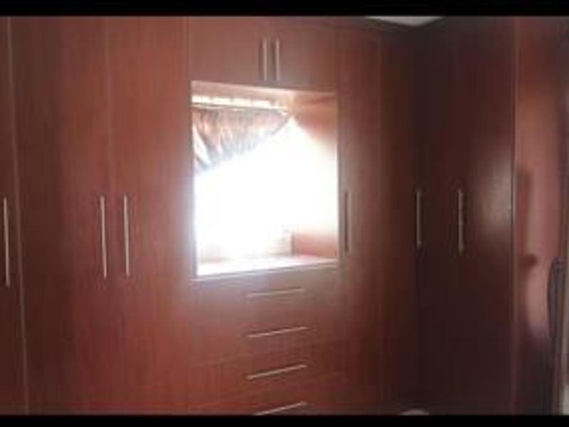 A bedroom featuring extensive dark wood built-in cabinetry with integrated drawers and a central window alcove.