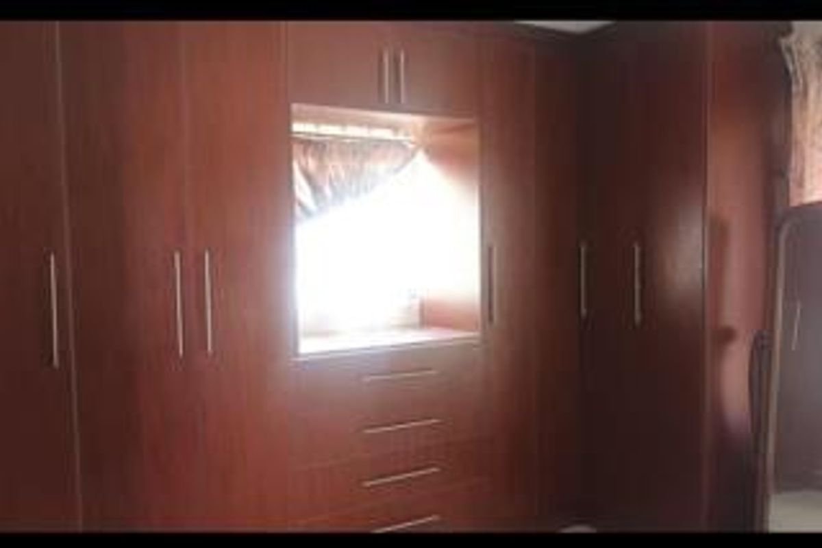 A bedroom featuring extensive dark wood built-in cabinetry with integrated drawers and a central window alcove.