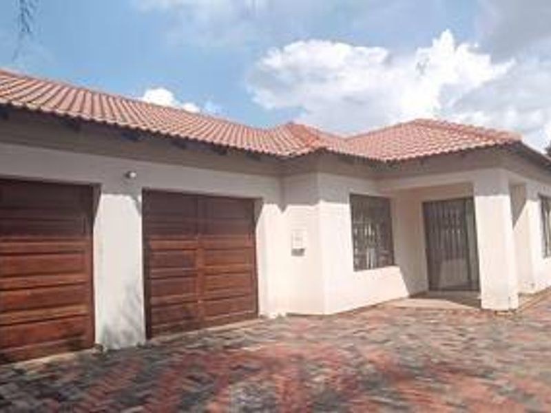 Front elevation of a residential house featuring a double garage, tiled roof, and a paved driveway.