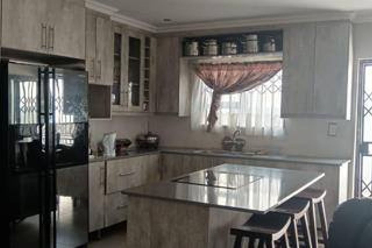 A functional kitchen featuring light-toned cabinetry, a central island with a built-in hob, and ample storage space.
