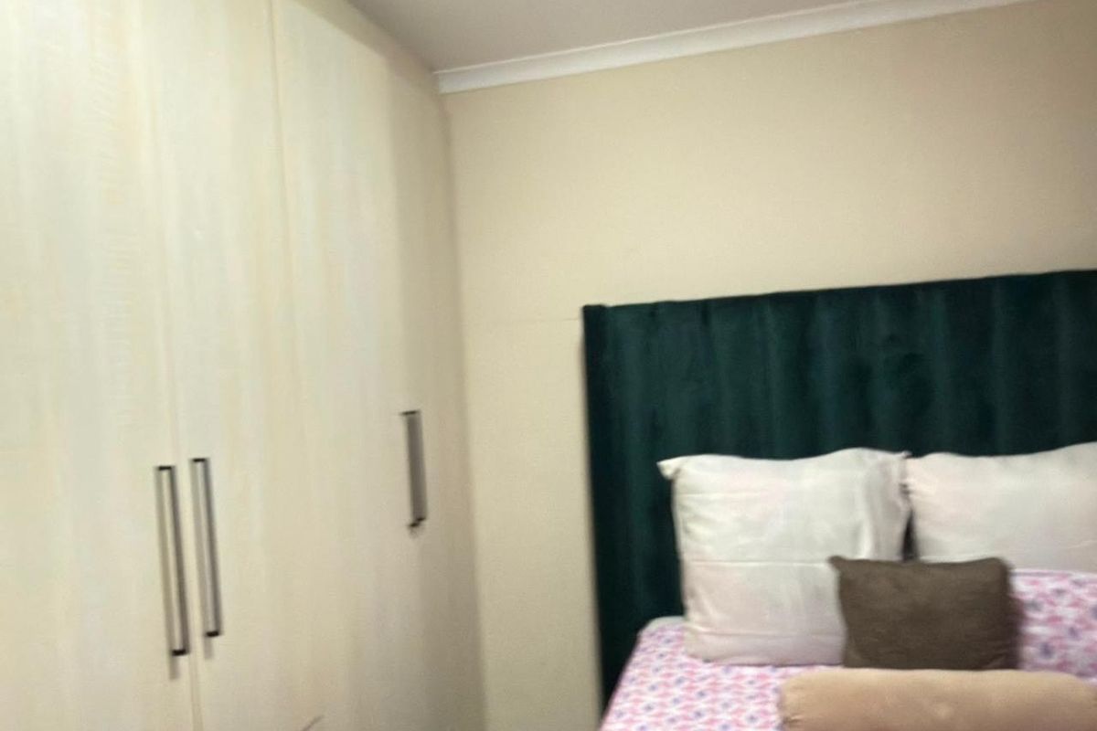 A bedroom featuring built-in cupboards with modern handles and neutral wall finishes.