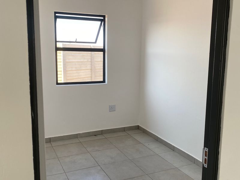 A clean, empty bedroom featuring neutral tiled flooring, white walls, and a top-hung window, providing a blank canvas for personalization.