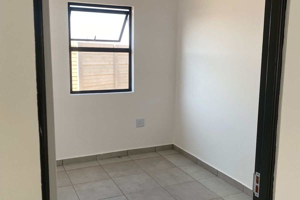 A clean, empty bedroom featuring neutral tiled flooring, white walls, and a top-hung window, providing a blank canvas for personalization.