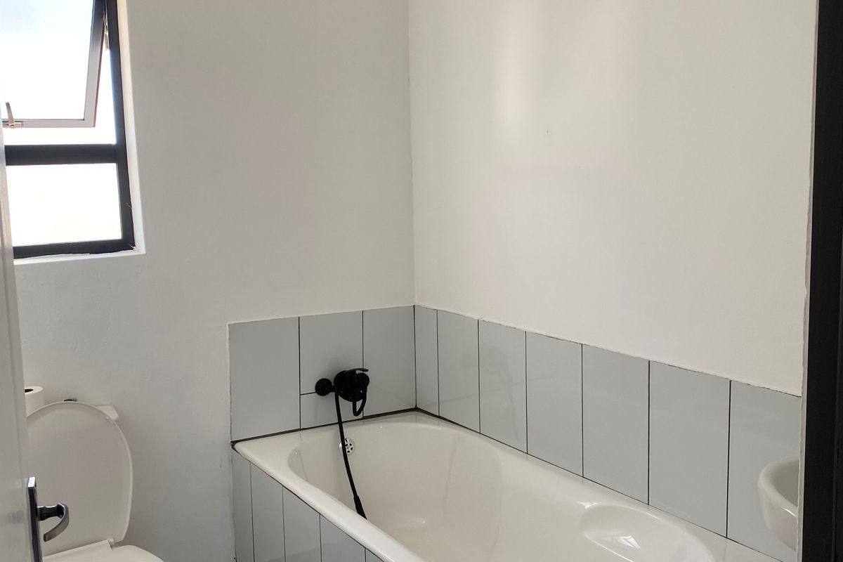 A clean, functional bathroom featuring a bathtub, toilet, tiled flooring, and a neutral color palette, ready for personal finishing touches.