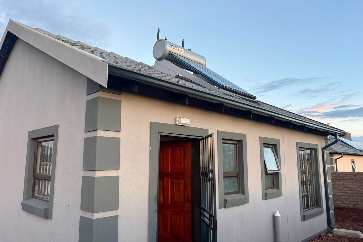 Rear view of the property featuring a tiled roof with an installed solar water heater, aluminium window frames, and a secure entrance.