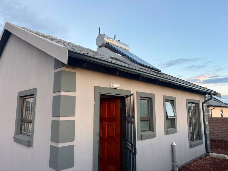 Rear view of the property featuring a tiled roof with an installed solar water heater, aluminium window frames, and a secure entrance.