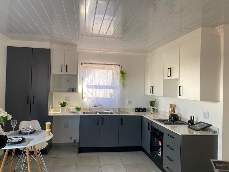 Modern kitchen featuring two-tone cabinetry, built-in oven and hob, double sink, and tiled flooring with a clean, contemporary finish.