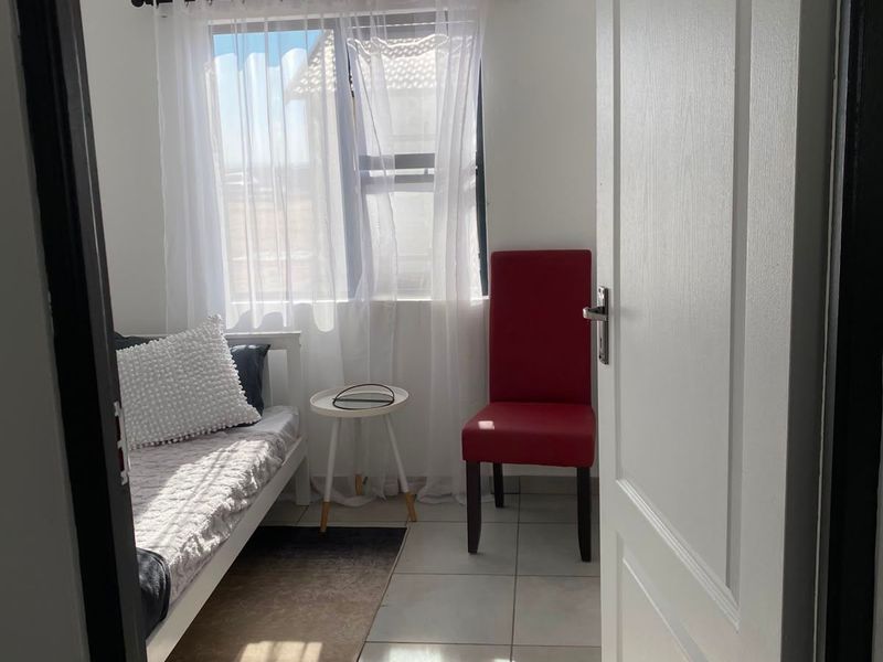 A compact bedroom featuring tiled flooring and a tongue and groove ceiling, viewed through an open doorway.