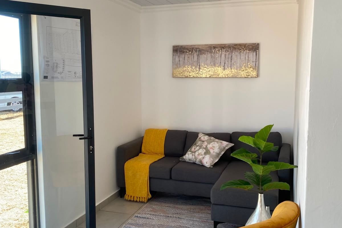A bright living area featuring tiled flooring, a tongue and groove ceiling with recessed lighting, and a modern aluminium framed glass door.