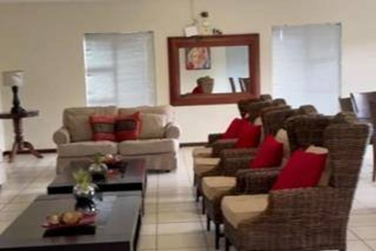 A spacious living area featuring neutral tiled flooring and window blinds, providing a functional base for comfortable seating arrangements.