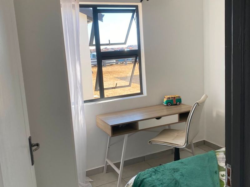 A compact bedroom featuring tiled flooring, a modern aluminium window frame, and a clean tongue and groove ceiling finish.
