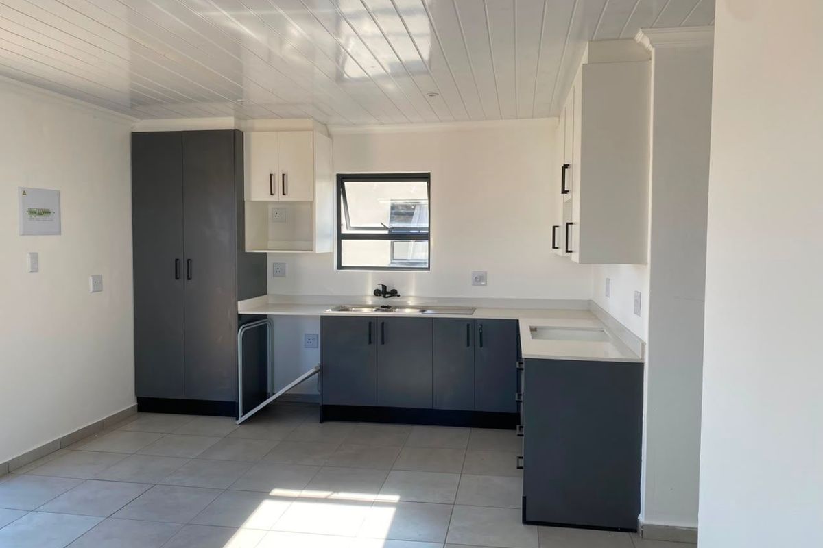 A clean, modern kitchen featuring two-tone cabinetry, tiled flooring, and a tongue and groove ceiling, offering a functional and bright workspace.