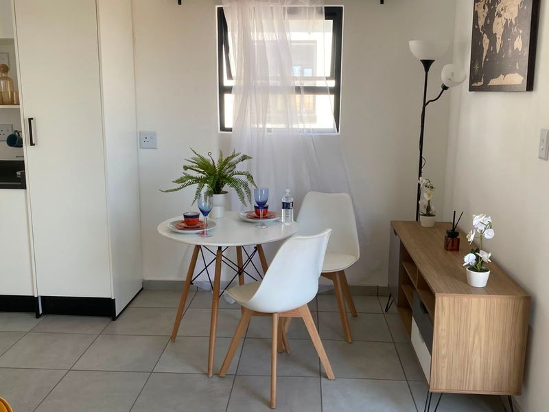 A bright dining area featuring neutral tiled flooring, built-in cabinetry, and a top-hung window, providing a clean and functional space.