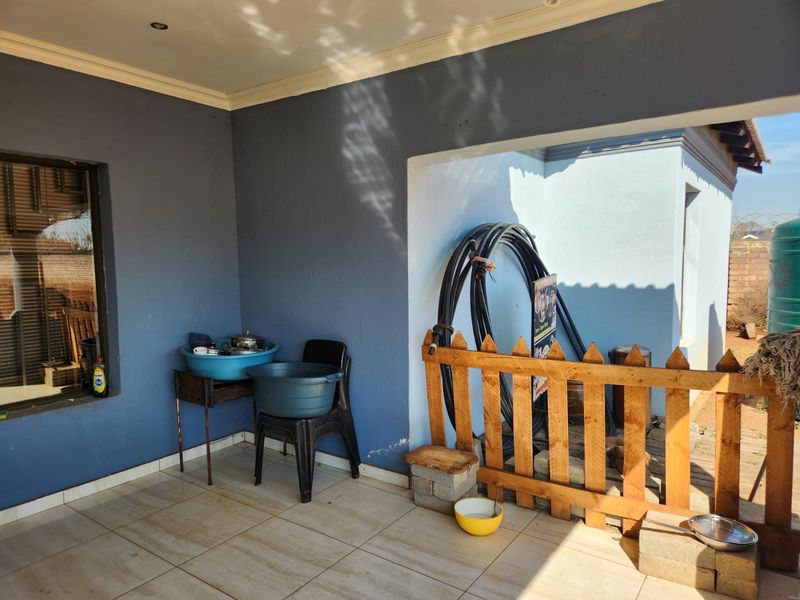 A covered patio area featuring tiled flooring, recessed lighting, and a wooden picket fence enclosure.