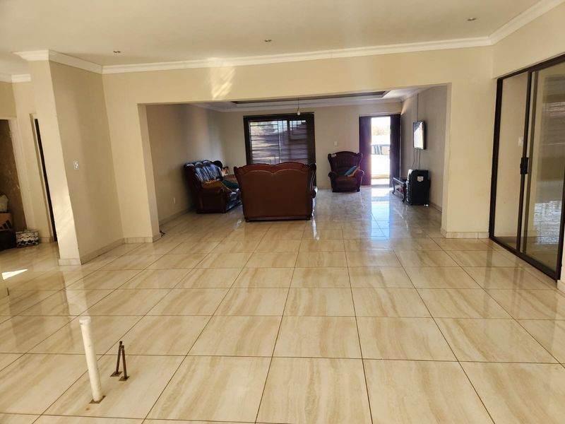Spacious open-plan living area featuring large format floor tiles, recessed lighting, and sliding glass doors leading to the exterior.
