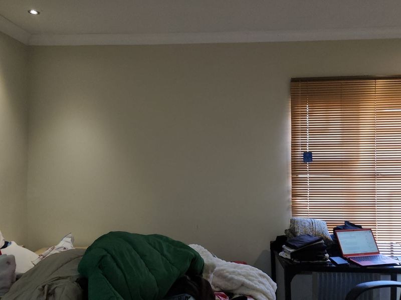 A bedroom featuring neutral wall finishes, recessed downlighting, and fitted venetian blinds.