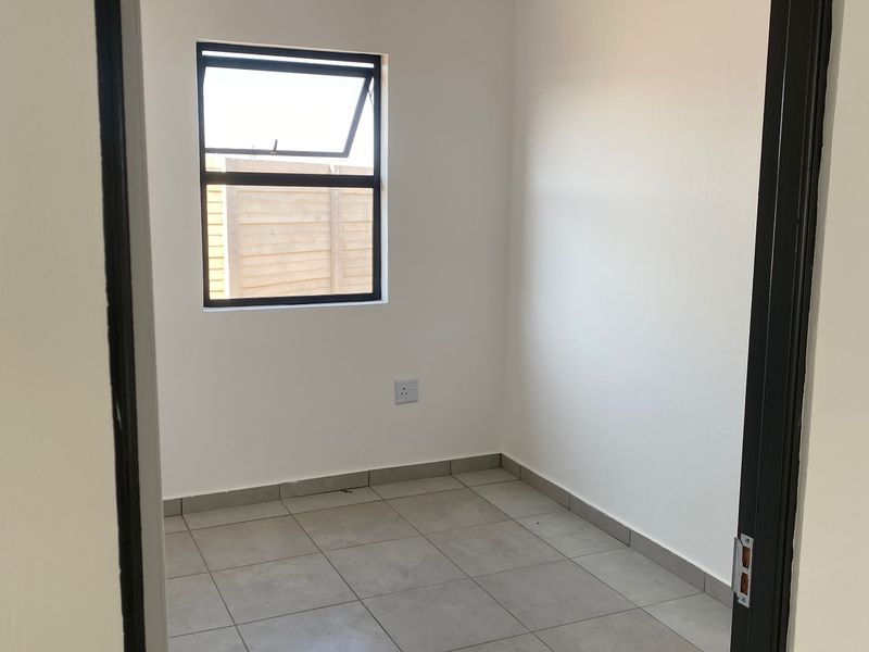 A clean, empty bedroom featuring neutral tiled flooring, white walls, and a functional top-hung window, ready for personalization.