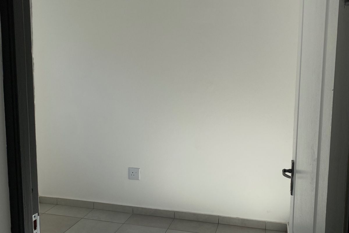 A bright, empty bedroom featuring neutral tiled flooring and a clean tongue and groove ceiling with recessed lighting.