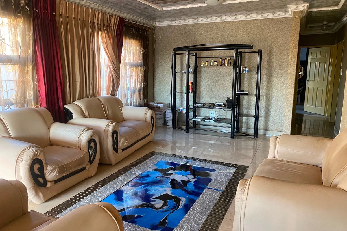 A living room featuring tiled flooring, textured wall finishes, and decorative ceiling molding, offering a dated but functional space for relaxation.